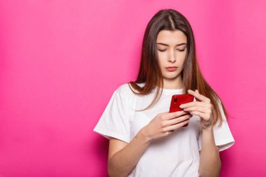 Gülümseyen esmer kadın, soluk pembe duvar arka plan stüdyo portresi üzerinde izole poz veriyor. İnsanların yaşam tarzı konsepti. Kopyalama alanı oluşturun. Cep telefonu kullanmak, SMS iletisi yazmak