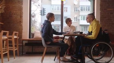 Kafedeki tekerlekli sandalyedeki mutlu genç adam arkadaşlarıyla iletişim kuruyor. Çeşitli takımlar kafede birlikte çalışıyor, bir online teknoloji firması pazarlama stratejisi için beyin fırtınası yapıyorlar..
