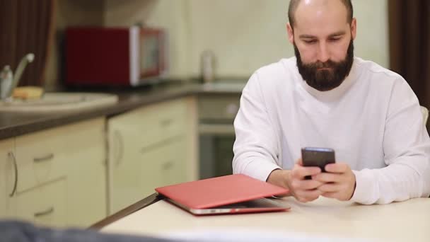 Schöne Millennial Single Kerl Sitzen Tisch Der Küche Halten Smartphone — Stockvideo