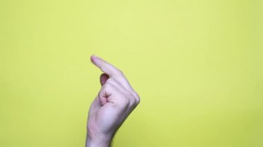Closeup view 4k video of man isolated on yellow background showing middle finger making Fuck you gesture. Bad and offensive expressions concept.