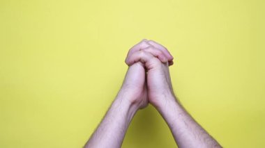 Adam ellerini birleştirir ve kollarını sarı arka planda gezdirir. 4k görüntü