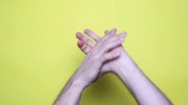 Tanınmayan bir adam ellerini sarı arka planda yoğurur. İnsan eli yoğurmaya yakın çekim, 4K görüntü.