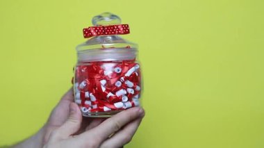 Kırmızı kurdeleli bir adamın eline yakın çekim. Noel, yeni yıl, doğum günü, Sevgililer Günü, uluslararası kadınlar günü sürprizi. Kişi sarı kutuda duruyor, 4k görüntü