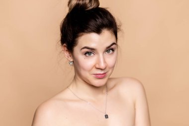 Güzel surat. Doğal makyajı ve sağlıklı deri portresi olan bir kadın. Güzel Asyalı manken bej arka planda taze, parlak, hidratlı cilde dokunuyor. Cilt bakımı kavramı