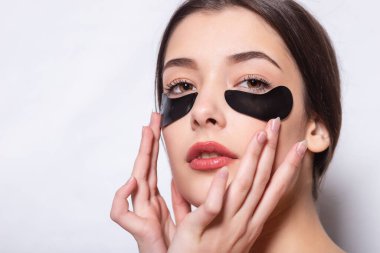 Göz bandı, doğal makyajlı güzel bir kadın ve yüz derisinde siyah jel göz bantları.