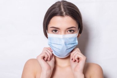 Hava yüzünden tıbbi maske takan güzel bir kadın. Coronavirus 'un beyaz arka planında izole edilmiş, göz makyajlı güzel Asyalı kadın..