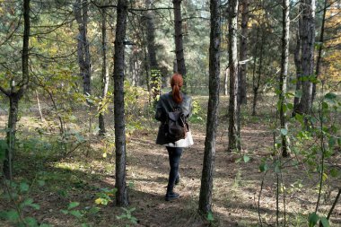 Ormanda yürüyen güzel kızıl saçlı aktif bir kız. Açık hava ormanı, sağlıklı yaşam tarzı konsepti.