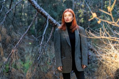 Aktif kızıl saçlı kız ormanda yürüyor.