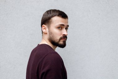 Beyaz tişörtlü, gri arkaplanda izole bir şekilde kameraya bakan gülümseyen yakışıklı adamın portresini yakından çek.