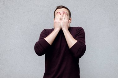 Sarışın, olgun bir adamın yüzünü ellerle örten, yüzünü göstermek istemeyen, anonim olmak istemeyen ya da sürpriz olmasını bekleyen fotoğrafının stüdyo fotoğrafı. Gri arkaplandaki vesikalık