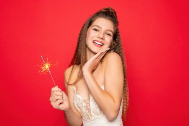 Havai fişekler ve insan konsepti - gülümseyen genç kadın veya genç kız maytaplı mutlu kadın kırmızı arka planda beyaz elbiseyle kutluyor.