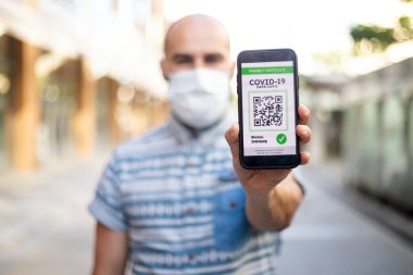 Covid-19 Koruma Konsepti. Elinde dijital sağlık pasaport başvurusu olan mutlu genç adam, aşıyı onaylıyor, seyahate hazır.