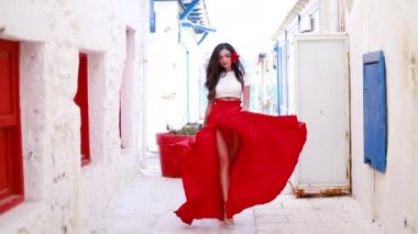 Happy woman in red long skirt and with a red flower in her hair. Young woman is wearing red dress and sunhat enjoying her Europe vacation