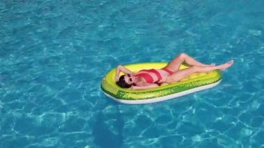 Havuzda kullanılan şişme avokado şiltenin üzerinde bikinili yaz tatilindeki kadın. Yaz, tatil, rahatla..