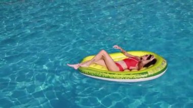 Havuzda kullanılan şişme avokado şiltenin üzerinde bikinili yaz tatilindeki kadın. Güneş banyosu yapan bir kızın tatil tatillerinin keyfini çıkardığı en iyi manzara. Lüks yaşam tarzı.