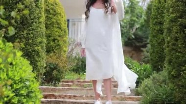 Beyaz elbiseli, elinde hasır şapkayla gezen, eski şehir caddesine bakan genç bir kadın..