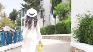 Kız Positano sokaklarında yürüyor. İtalya. Beyaz elbiseli gösterişli esmer merdivenlerden çıkıyor. Yavaş çekim