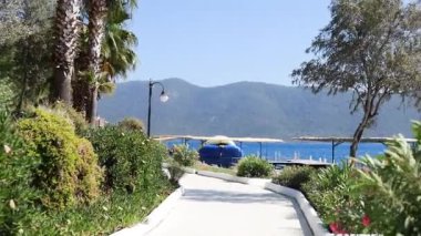 Sabit, sabit bir kumsalın güzel manzarasıyla yürüyorum. Lüks otellerin üzerinde uçmak bungalov, turkuaz mavi su ve palmiye ağaçları.