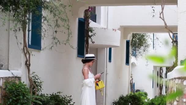 드레스를 모자를 걸어서 호텔을 둘러보는 여성이 있습니다 네트워크에서 아이의 메시지 — 비디오