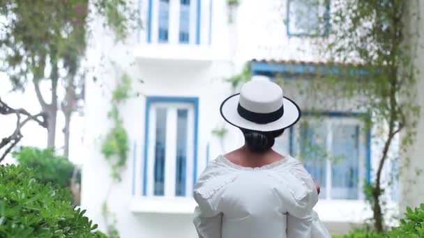 Eine junge Frau wendet sich in einem weißen Kleid der Kamera zu und geht durch die Straßen Griechenlands