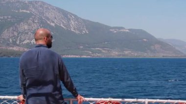 Dağlar ve turkuaz sularla bir deniz yatında yüzen Kafkasyalı bir gezgin. Deniz kenarında yaz tatili. Yüzme, güneş banyosu seyahat tutkusu konsepti.