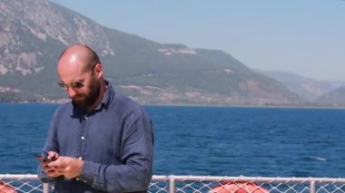 Dağlar ve turkuaz sularla bir deniz yatında yüzen Kafkasyalı bir gezgin. Sosyal ağlarda, yüzme, güneş banyosu gezintisi konsept sahnesinde yeniden yazıyor. Ağır çekim, 4k