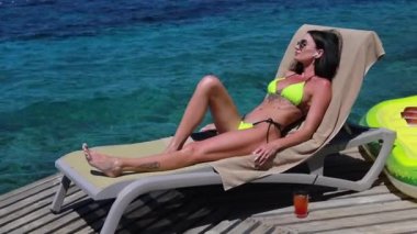 Lüks bir otelde rahat rahat uzanan zarif bir bayan. Kadın kolları havada, özgürlük ve lüks tatil konsepti kablosuz kulaklıkla müzik dinliyor.