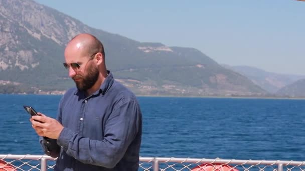 Кавказький Чоловік Плаває Узбережжі Яхти Горами Бірюзовими Водами Переписав Телефону — стокове відео
