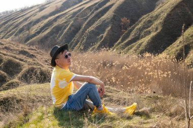 Genç bir adam bahar dağlarında gün batımında yanlamasına oturur ve doğanın tadını çıkarır. Dağ ve kıyı yolculuğu, özgürlük ve aktif yaşam tarzı