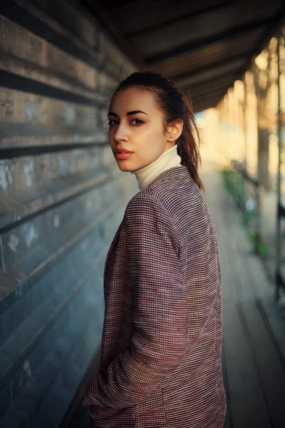 Jonge vrouw met een jas casual reputatie met stad achtergrond bij zonsondergang. Sexy aantrekkelijke mode styling afbeelding afgezwakt — Stockfoto