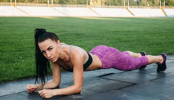 Slim athletic woman with dumbbells in the stadium — Stock Photo, Image