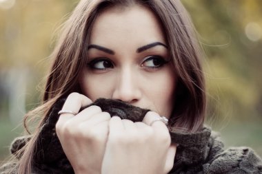 üzgün, esmer kadın bir atkı sarılı