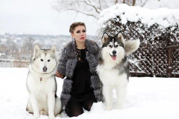 Młoda kobieta z psem wilk w śniegu — Zdjęcie stockowe