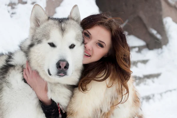 Jovem mulher com cão lobo na neve — Fotografia de Stock