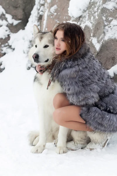 Young woman with wolf dog in snow