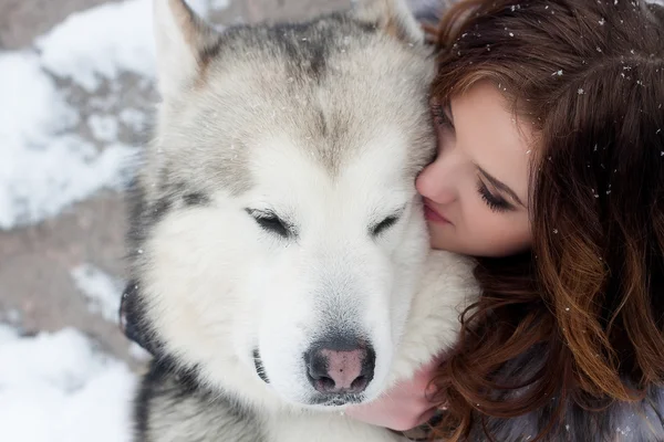Νεαρή γυναίκα με το σκυλί λύκων στο χιόνι — Φωτογραφία Αρχείου