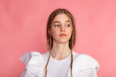 Pastel pembe arka plan, temiz güzellik ve modern tarz karşısında genç bir kadının önden çekilmiş portresi..