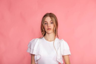 Centered upper-body portrait on pastel pink, natural beauty and clean wardrobe styling.