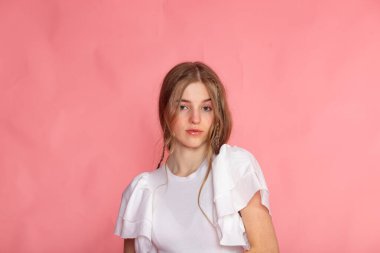 Sakin yüzü, beyaz bluzu ve pembe arkaplanı olan minimal stüdyo portresi, modern yaşam tarzı konsepti.