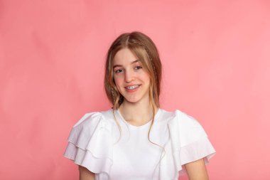 Açık gülümsemeli stüdyo portresi, pastel pembe arka plan, dostane yaşam tarzı ve güzellik konsepti..