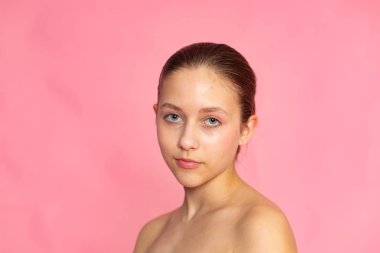 Pembe arka planda yumuşak ifadeli stüdyo güzelliği portresi, minimum estetik.