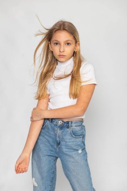 Kot pantolon ve beyaz tişörtle poz veren genç kız, günlük tarz ve temiz estetik..