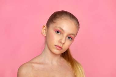 Pembe arka planda yakın plan, nazik gülümseme ve doğal ten, modern güzellik estetiği.