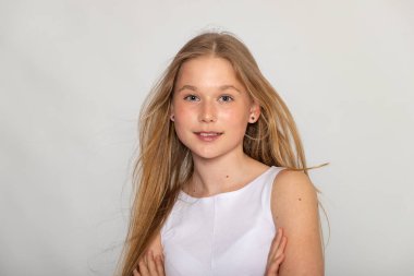 Hafif gülüşlü, sarı saçlı ve minimalist beyaz arka planlı bir stüdyo resmi..