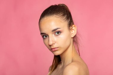 İnce gülüşlü güzel bir vesikalık, pembe renkli temiz stüdyo estetiği..