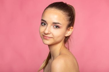 Pembe arka planda dostane bir güzellik portresi, doğal görünüş ve yumuşak ifade.