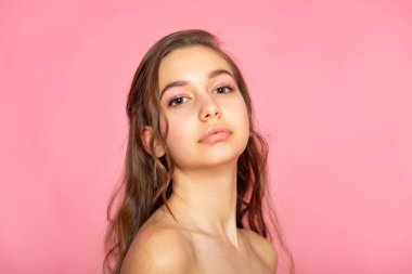Beauty portrait with gentle expression, pink background, clean skin focus.