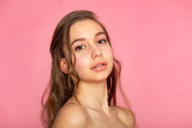 Headshot with slight head tilt, natural beauty and soft pink backdrop.