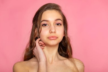 Elinin yanağına yakın olduğu güzel bir vesikalık, cilt bakımı ve pembe üzerine kişisel bakım konsepti.