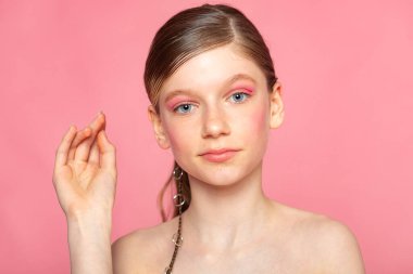 Kaldırılmış el hareketleriyle portre, pastel pembe arka planda yaratıcı güzellik pozu.